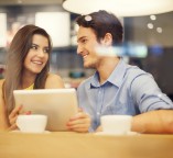 Flirting couple in cafe using digital tablet